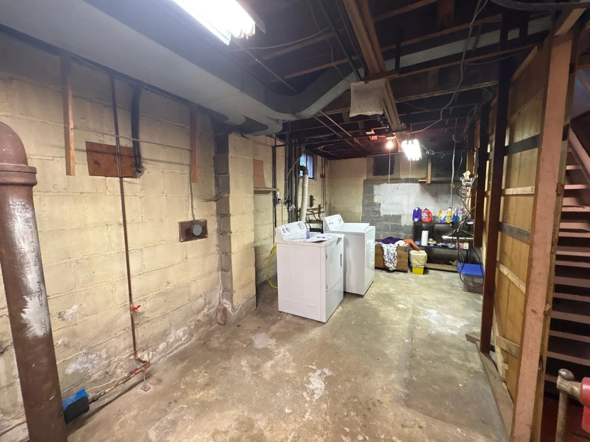 Unfinished basement in Hastings-On-Hudson, NY with visible moisture stains on foundation walls and concrete floor prior to interior waterproofing installation.